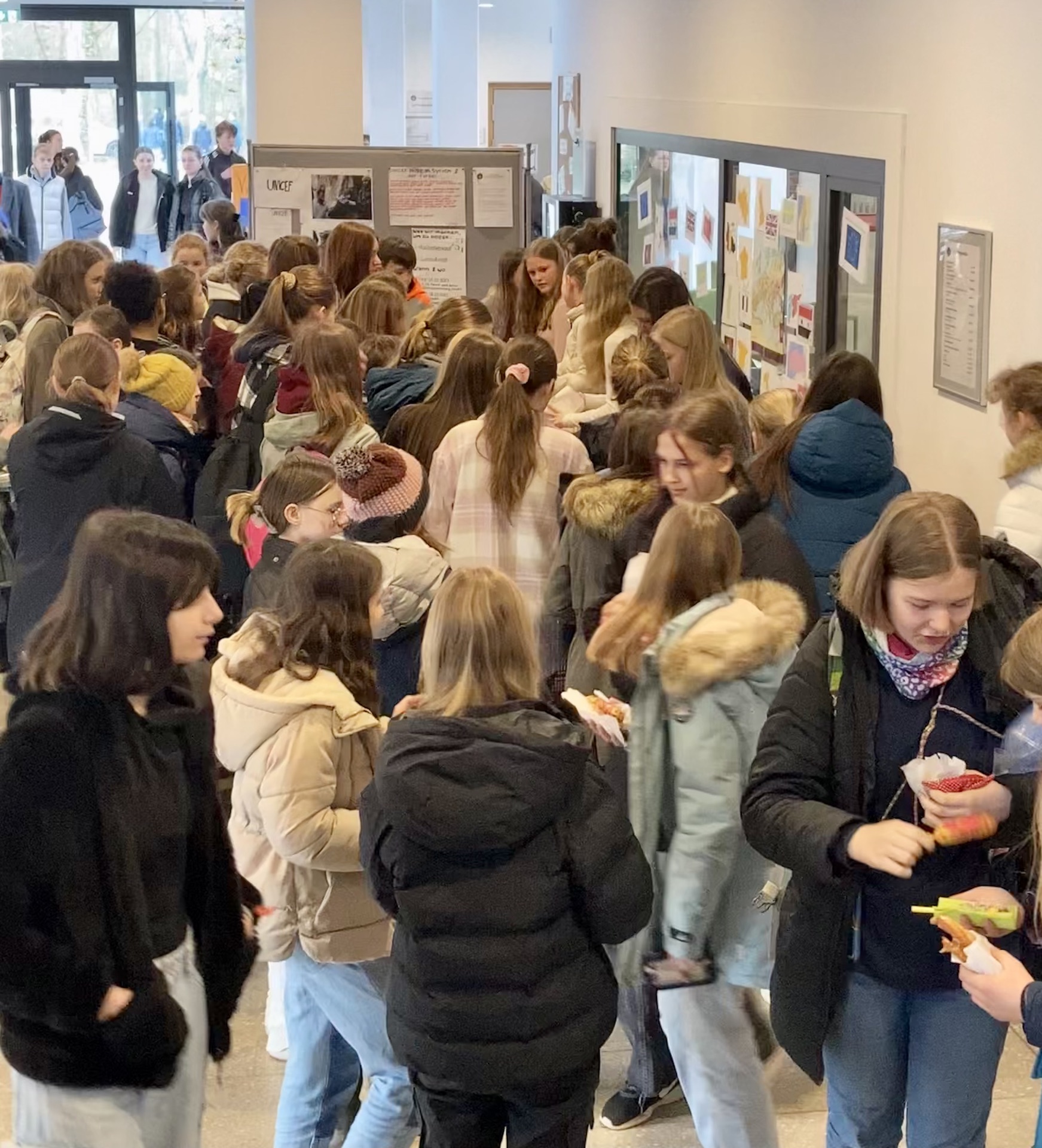 Schülerinnen und Schüler im Foyer vor einem Verkaufsstand mit Speisen