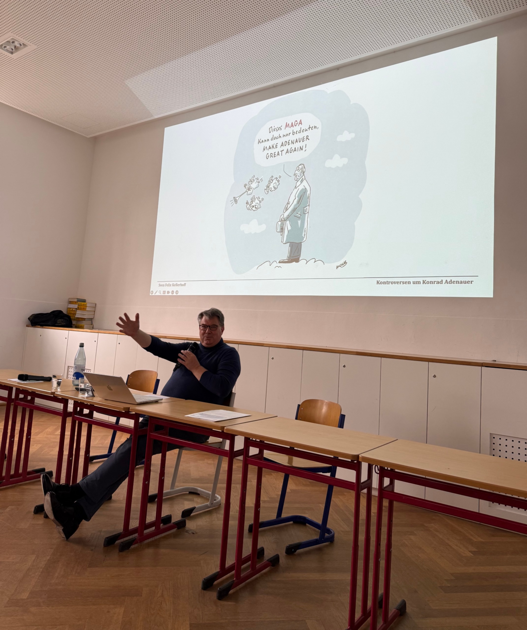 Vortragender sitzt vor Projektionsfläche mit Adenauer-Karikatur