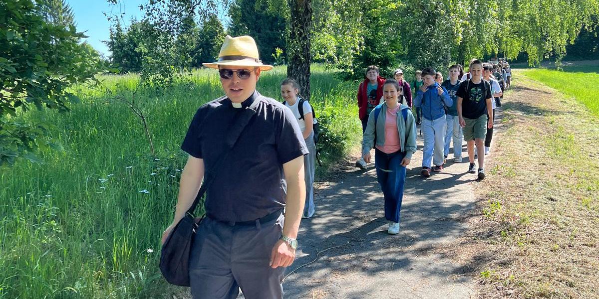 Priester auf Wanderweg, Kinder laufen dahinter