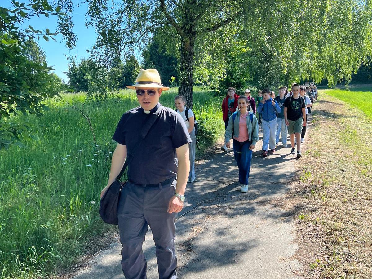 Priester auf Wanderweg, Kinder laufen dahinter