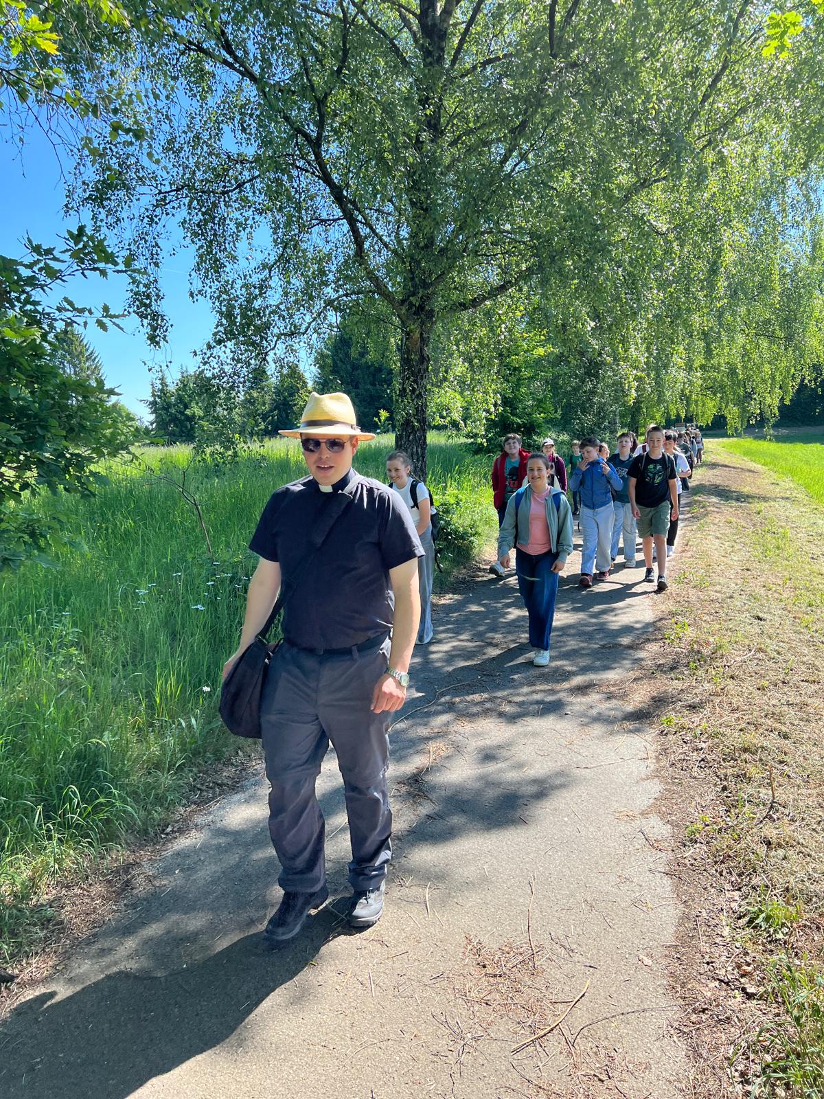Priester auf Wanderweg, Kinder laufen dahinter