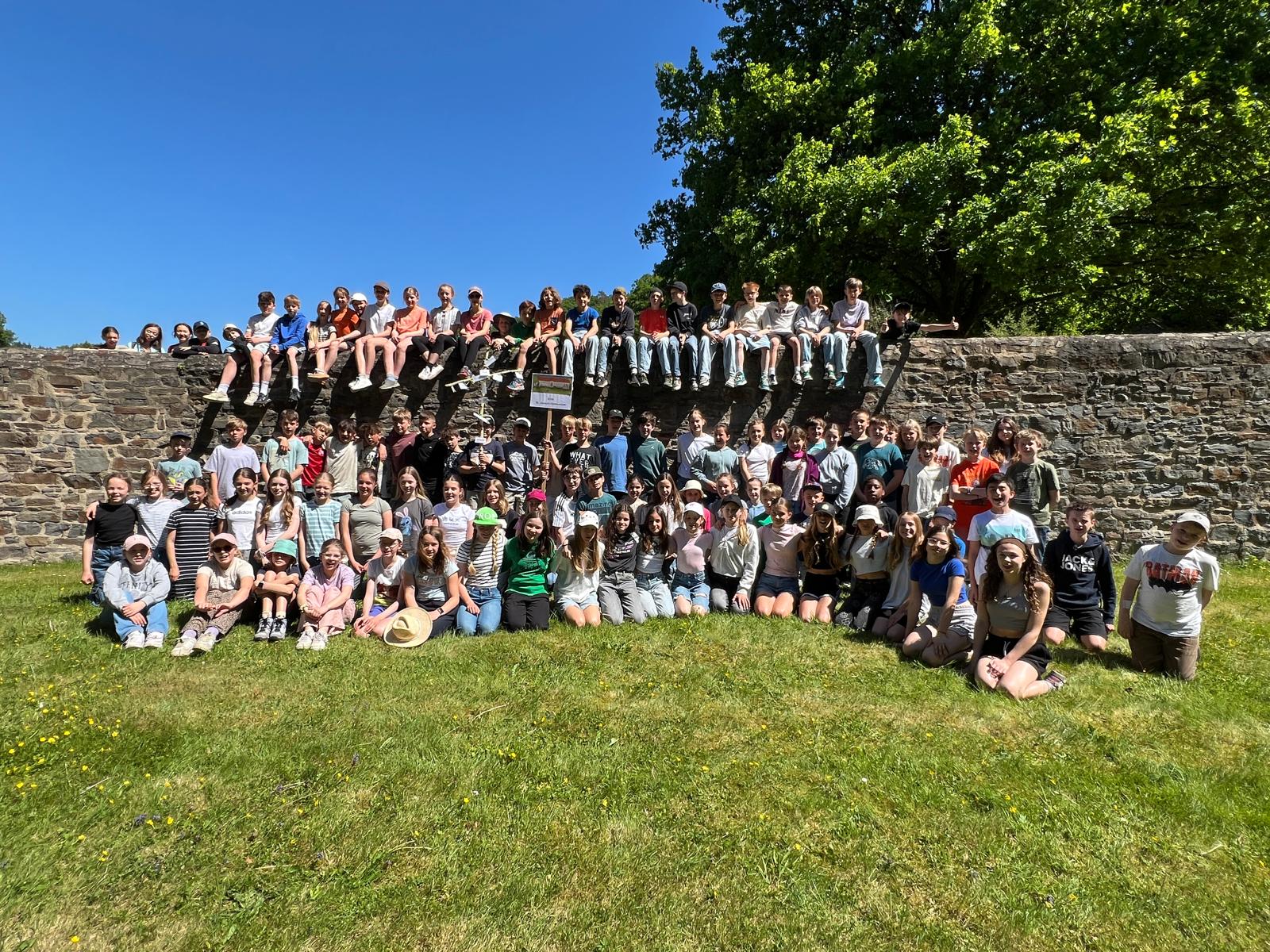 Gruppenbild mit Schüler:innen auf einer Wiese vor einer Mauer