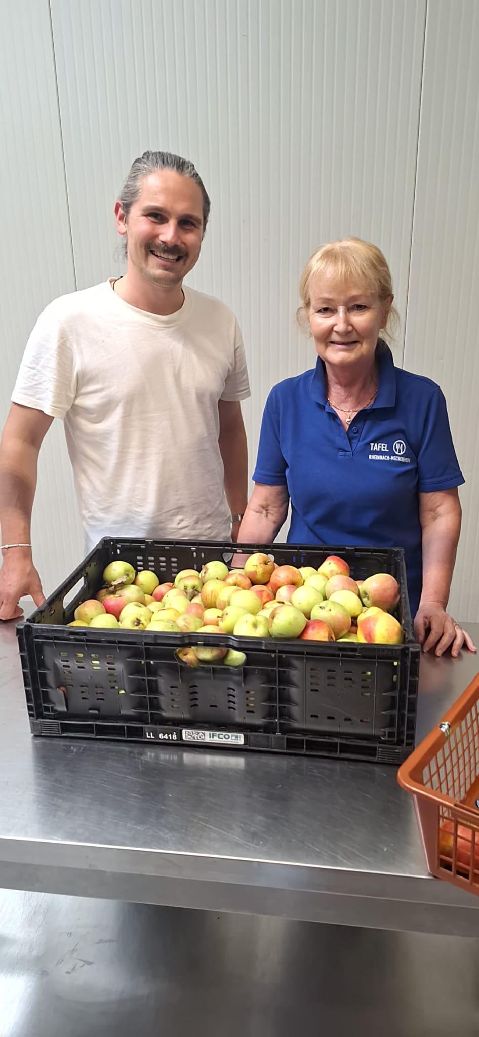 Mann und Frau, davor ein Plastikkorb voller Äpfel