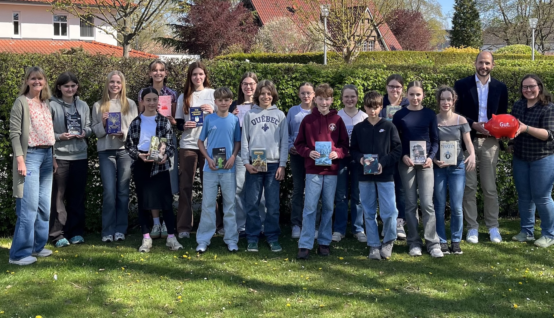 Gruppenfoto Schülerinnen und Schüler, Bücher in den Händen, seitlich jeweils Erwachsene