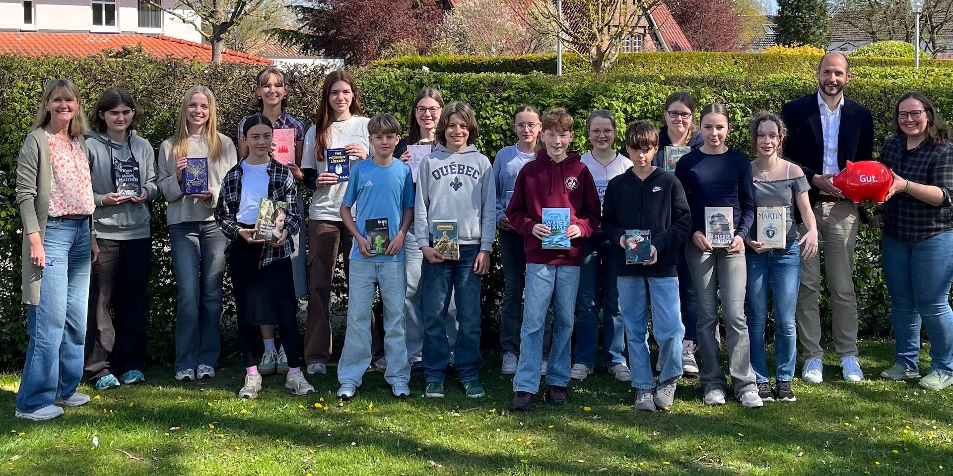 Gruppenfoto Schülerinnen und Schüler, Bücher in den Händen, seitlich jeweils Erwachsene