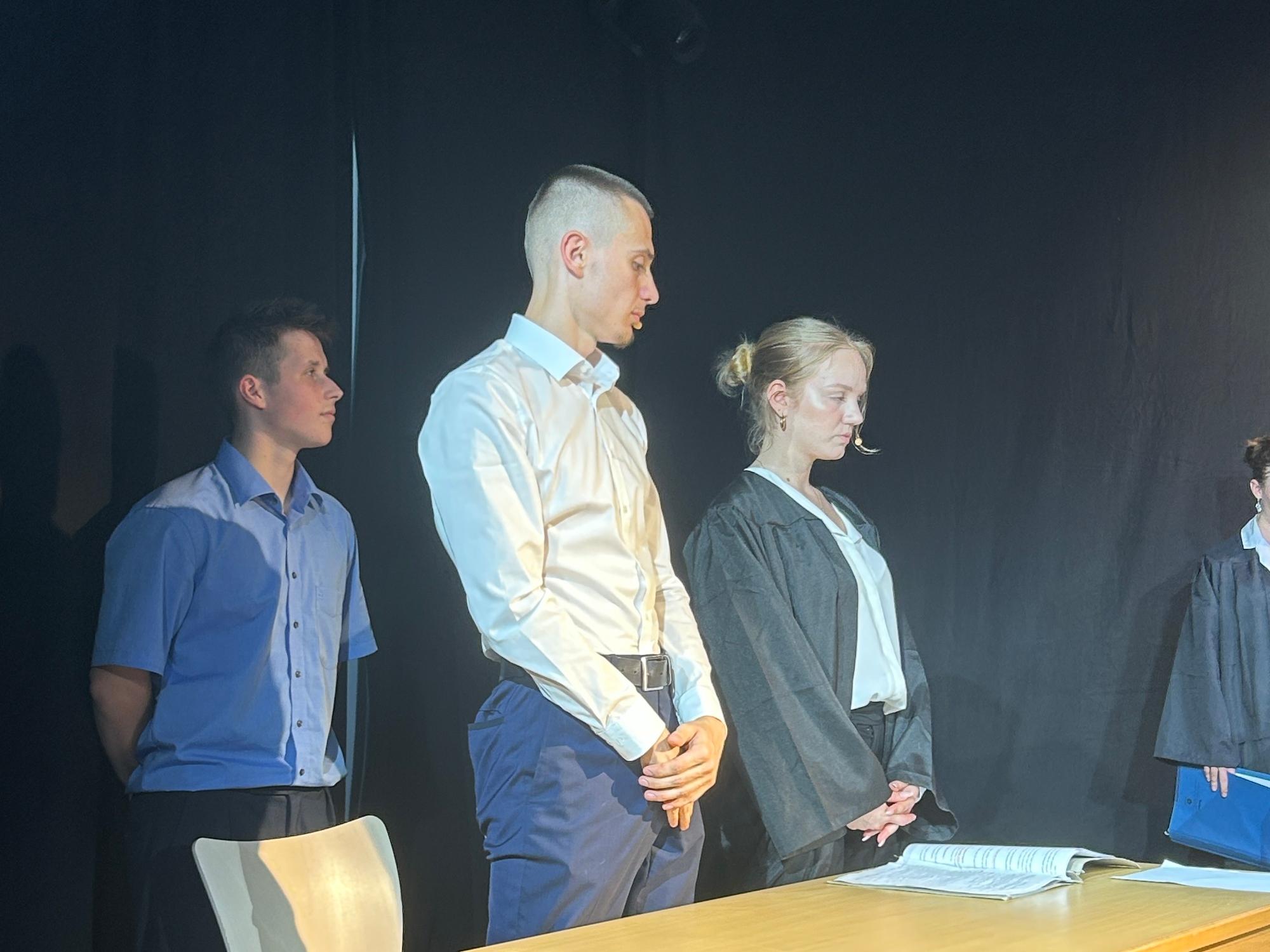 Schüler als Wächter, Schüler als Angeklagter, Schülerin als Rechtsanwältin auf der Bühne