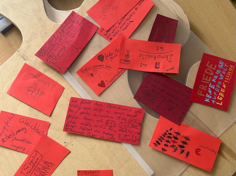beschriebene rote Zettel liegen auf einem Holzbrett, das die Form eines Puzzleteils hat