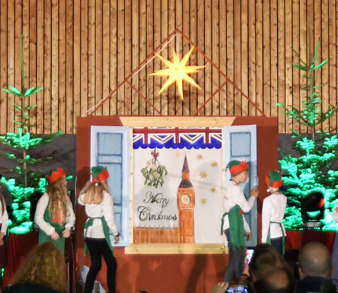 Kinder öffnen die Tür, dahinter ein Plakat zu England, Bühne mit Kindern