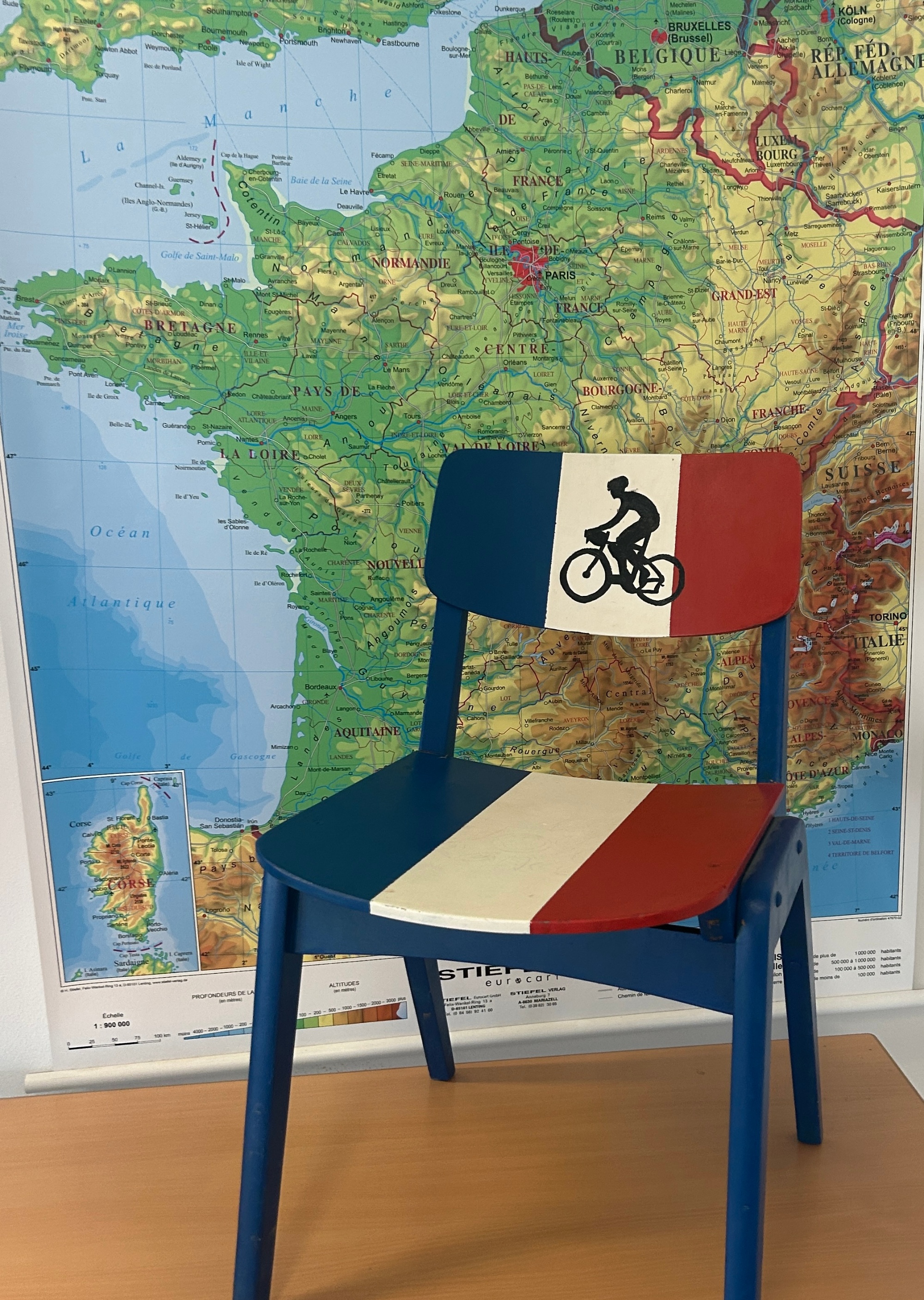 Stuhl: blau, weiß, rot gestreift bemalt, dahinter Landkarte von Frankreich