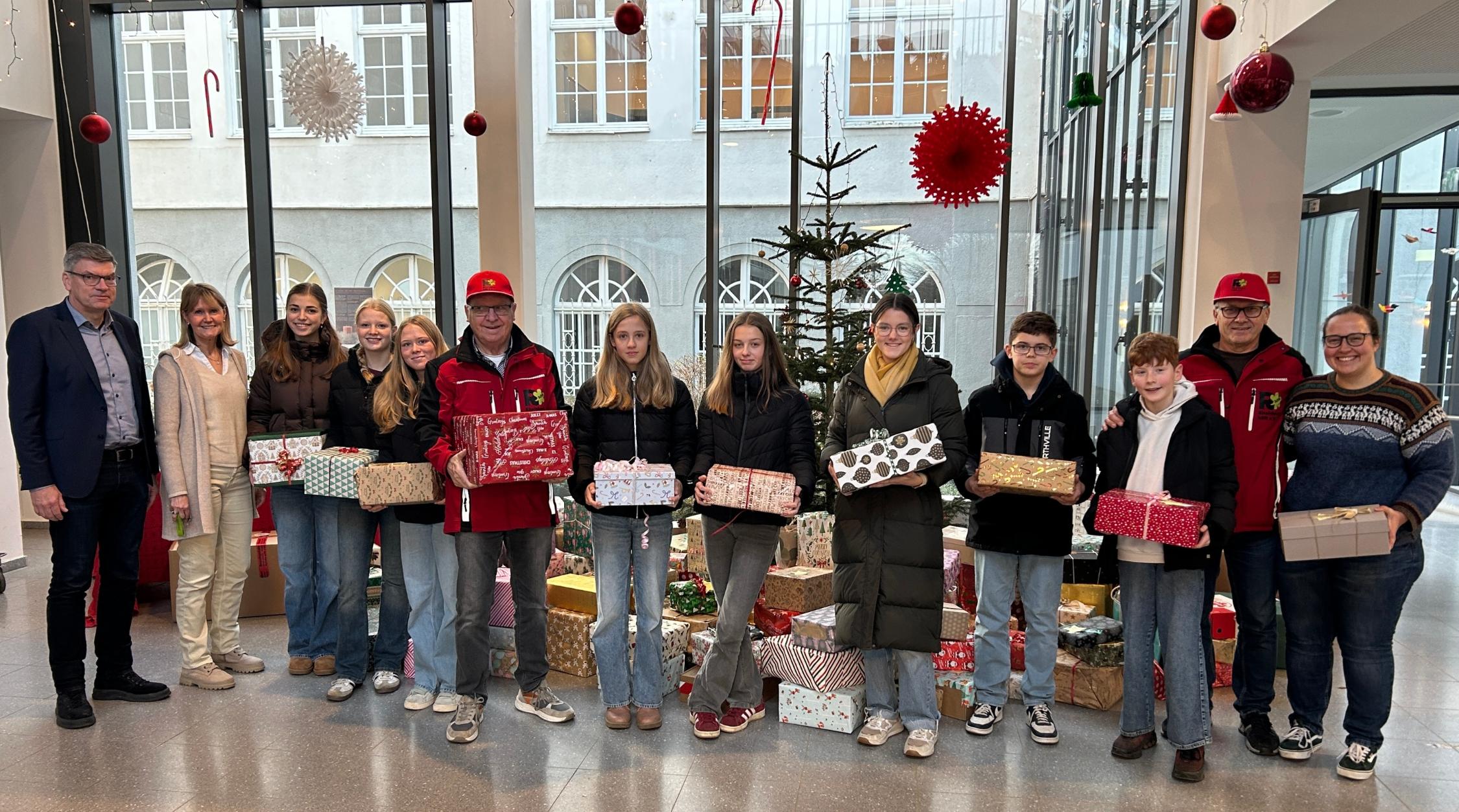 Gruppenbild Erwachsene und Schüler:innen, Geschenkpakete in den Händen