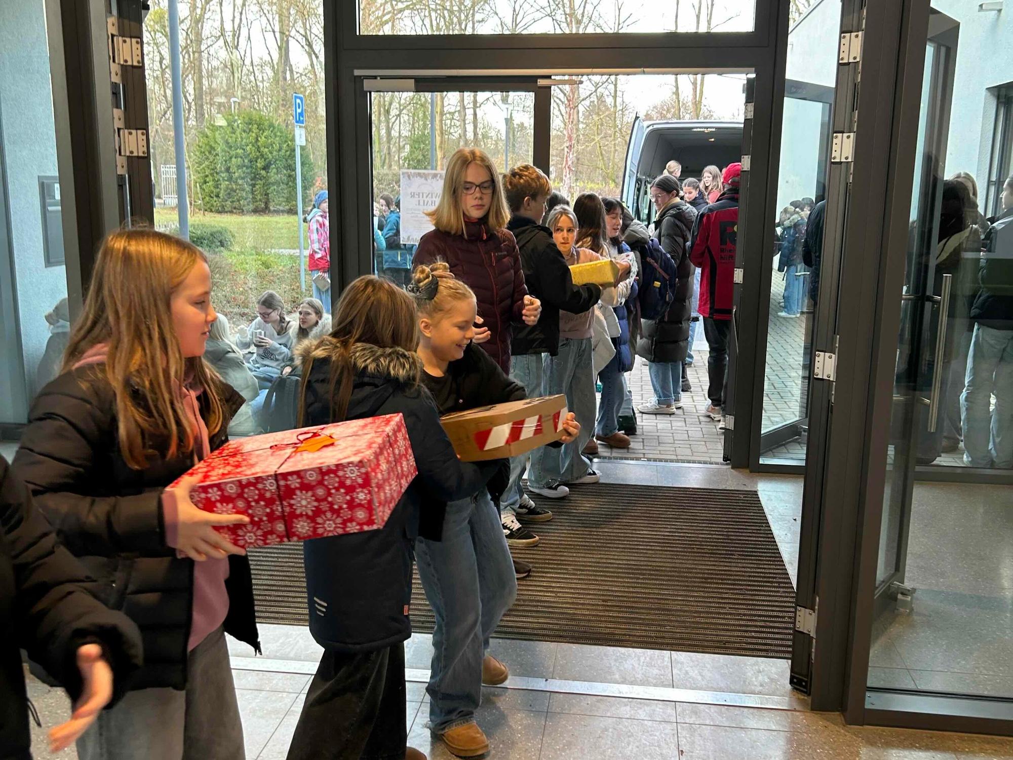 Schüler:innen geben eingepackte Geschenke von Hand zu Hand bis zum Lkw
