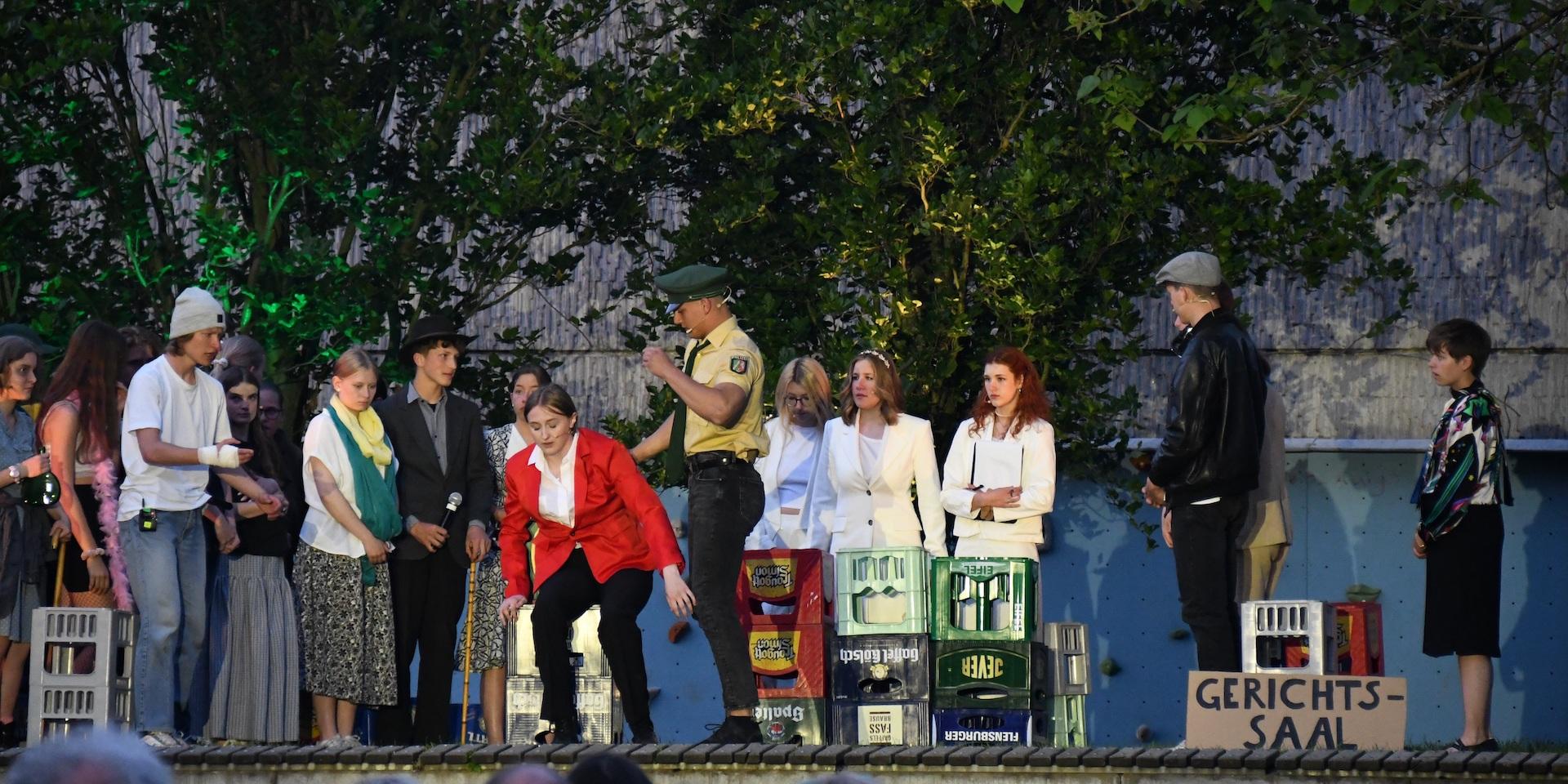 Open-Air-Bühne mit Schauspieler:innen in Chantals Kiosk, Mr. Jones vorn