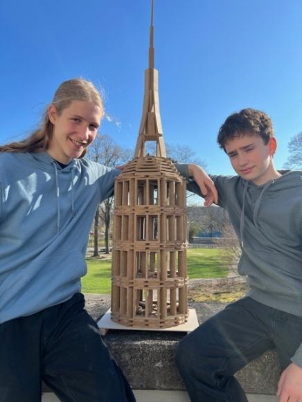zwei Schüler, in der Mitte ein Turm aus Holz