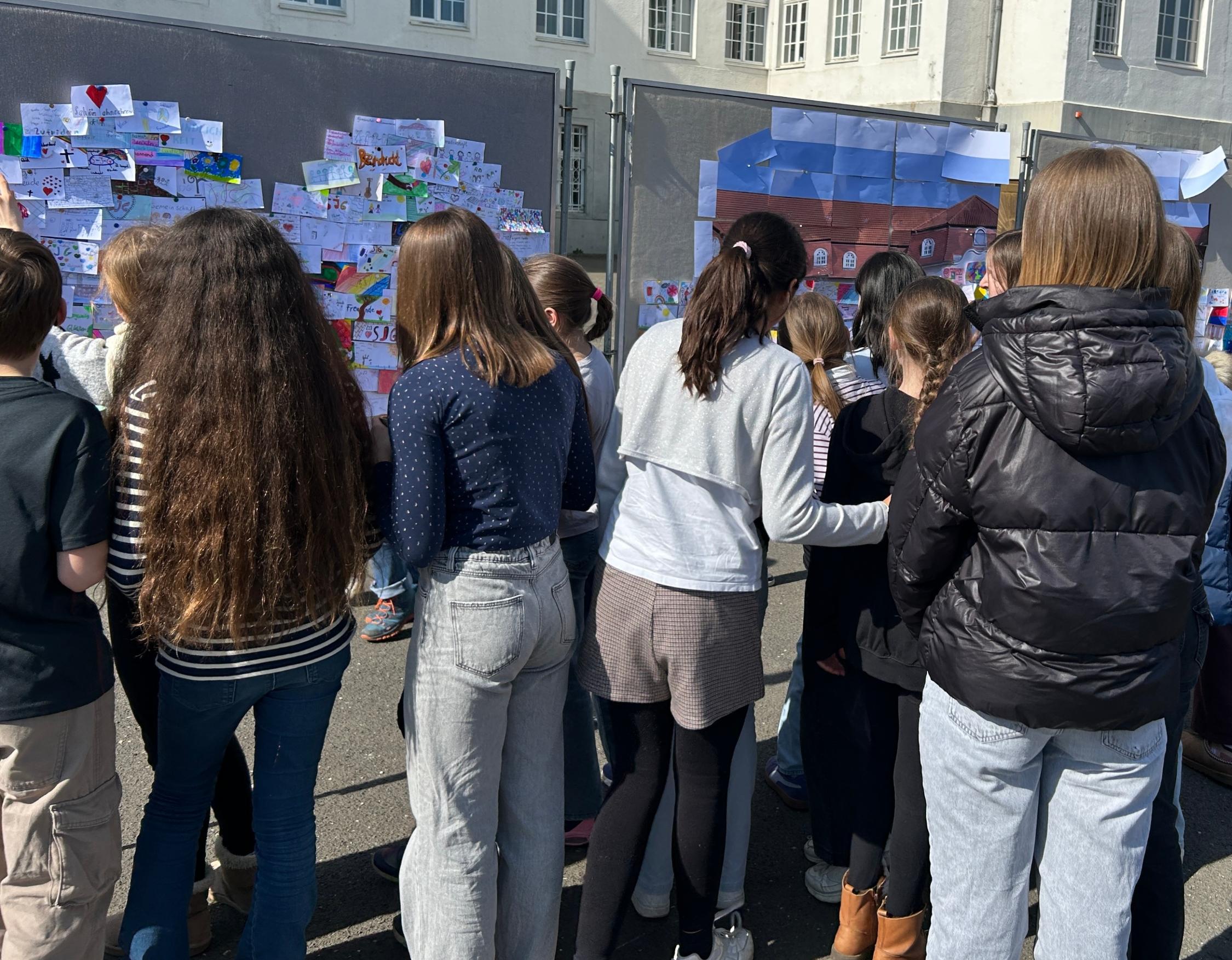 Schülerinnen betrachten die Pinnwand