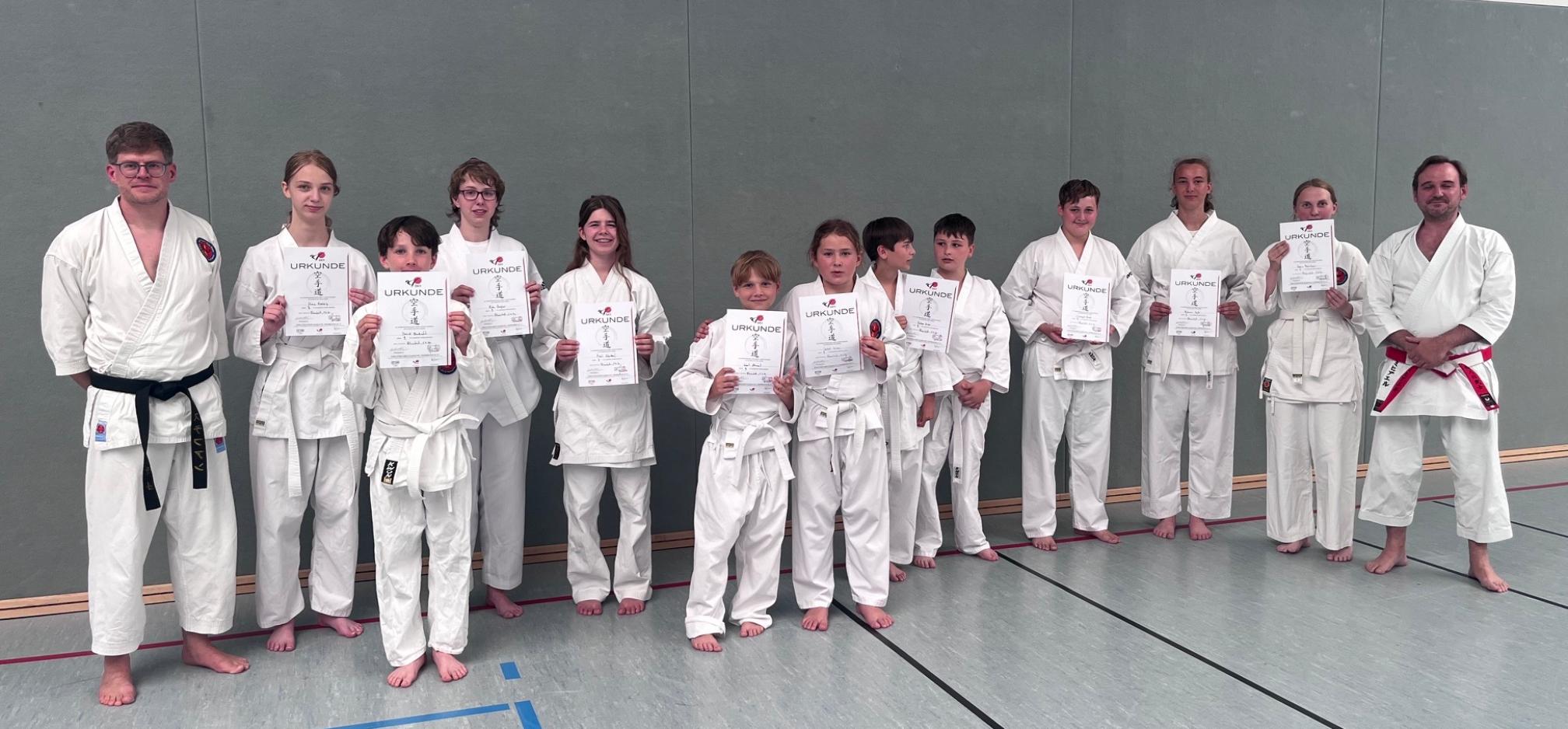 Jungen und Mädchen in Karate-Anzügen mit Urkunden in der Hand