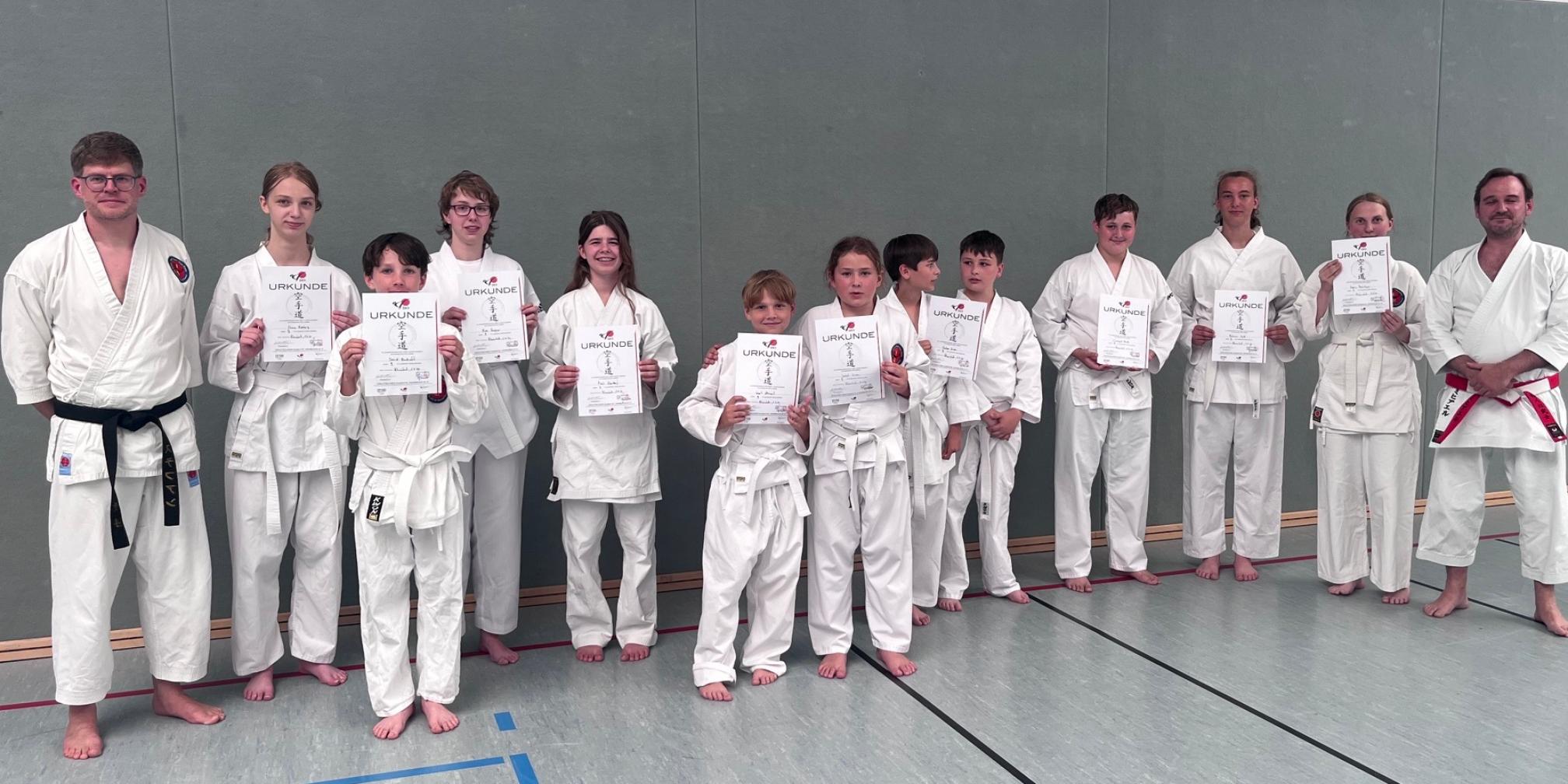 Jungen und Mädchen in Karate-Anzügen mit Urkunden in der Hand