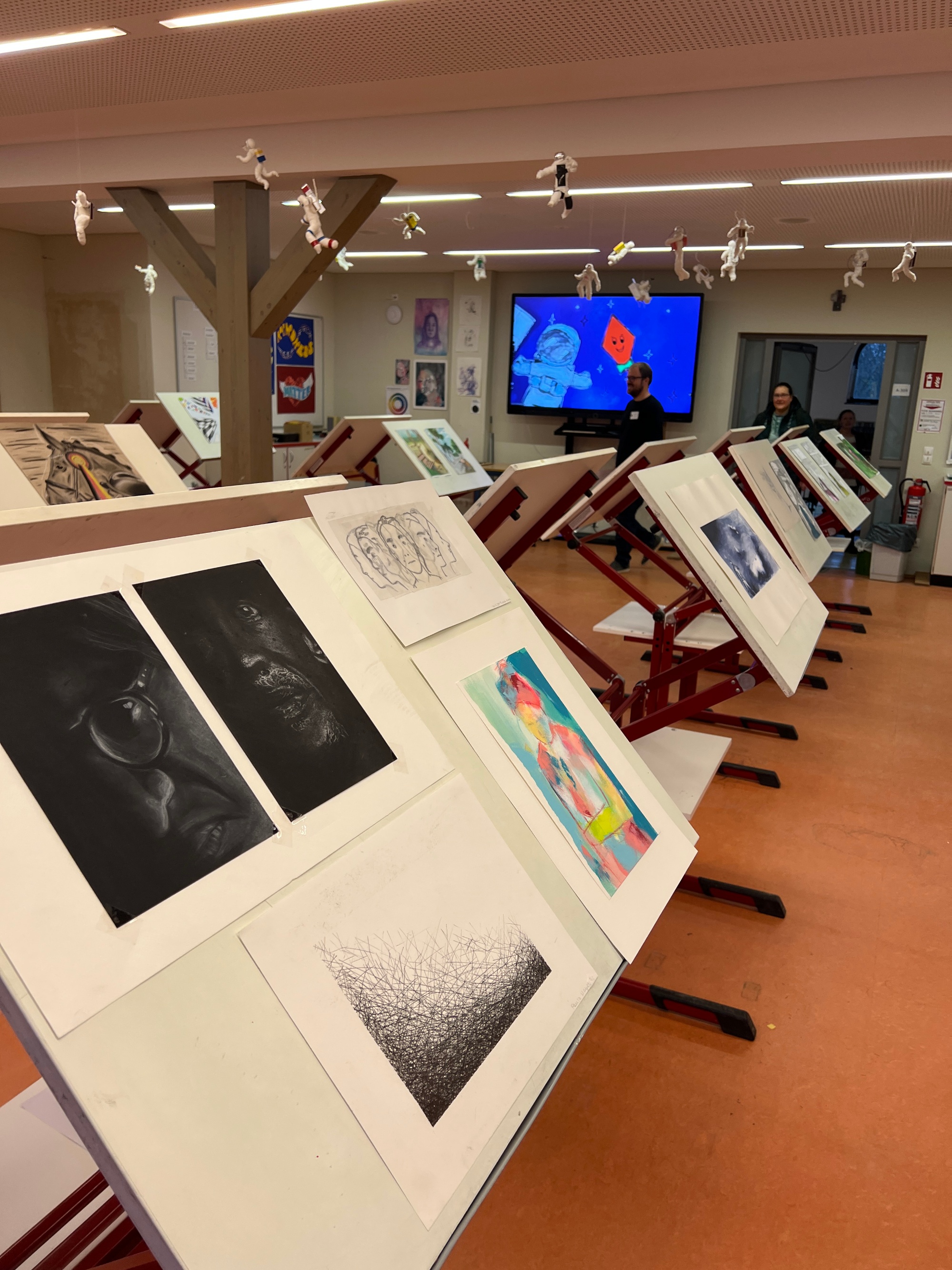 Schülerkunstwerke auf hochgeklappten Tischen im Kunstraum