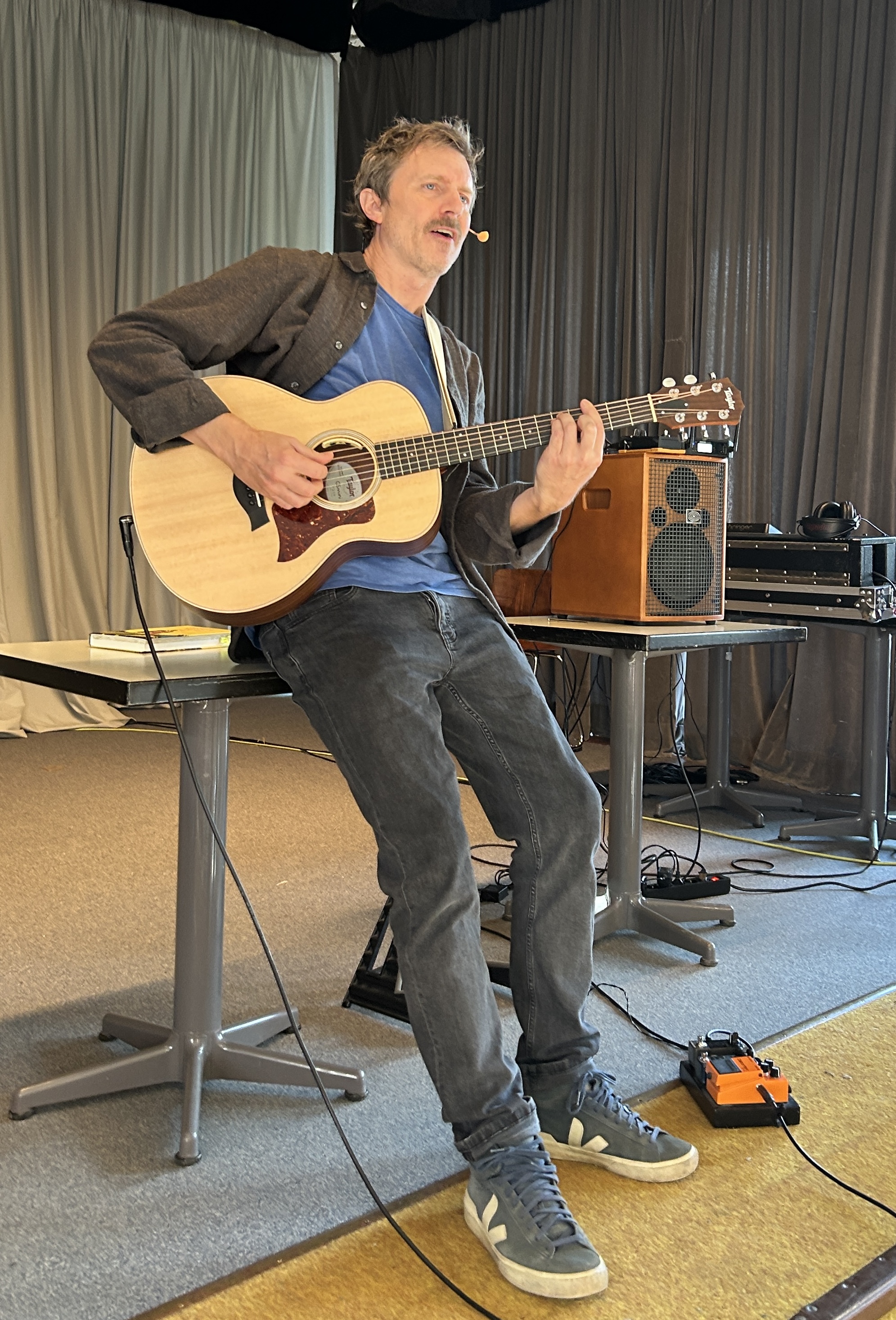 Mann spielt Gitarre und singt, lehnt sich nach hinten