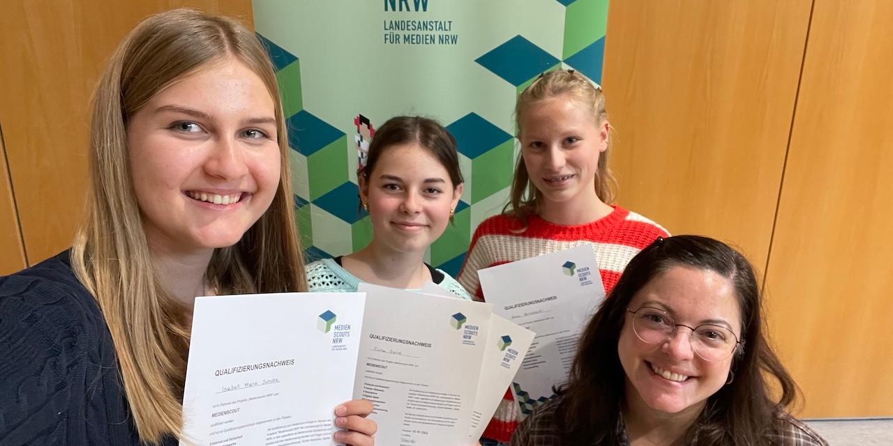 drei Mädchen mit Urkunden in der Hand, rechts eine Lehrerin