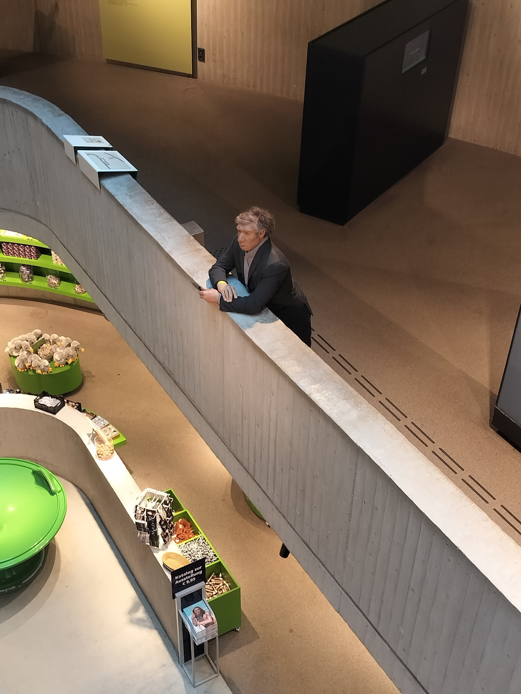 Neanderthal-Figur lehnt sich über die Brüstung im Museumsbau