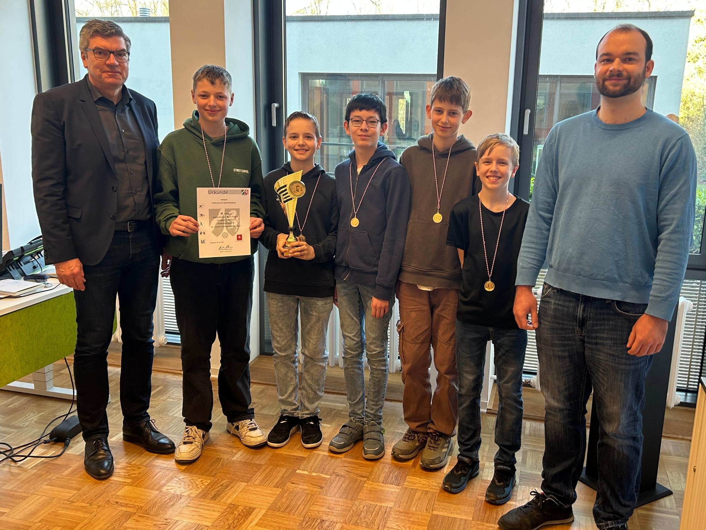Gruppenbild: fünf Jungen, am Rand zwei Männer, ein Junge hält eine Urkunde und einer einen Pokal in den Händen