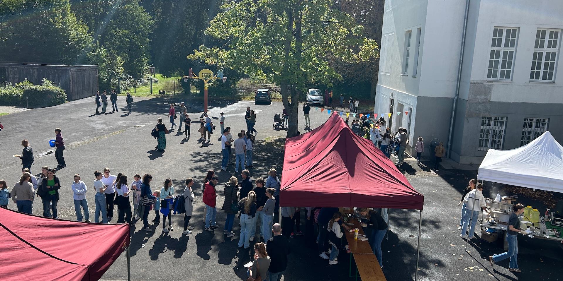 Schlange auf dem Schulhof vor einem Pavillon