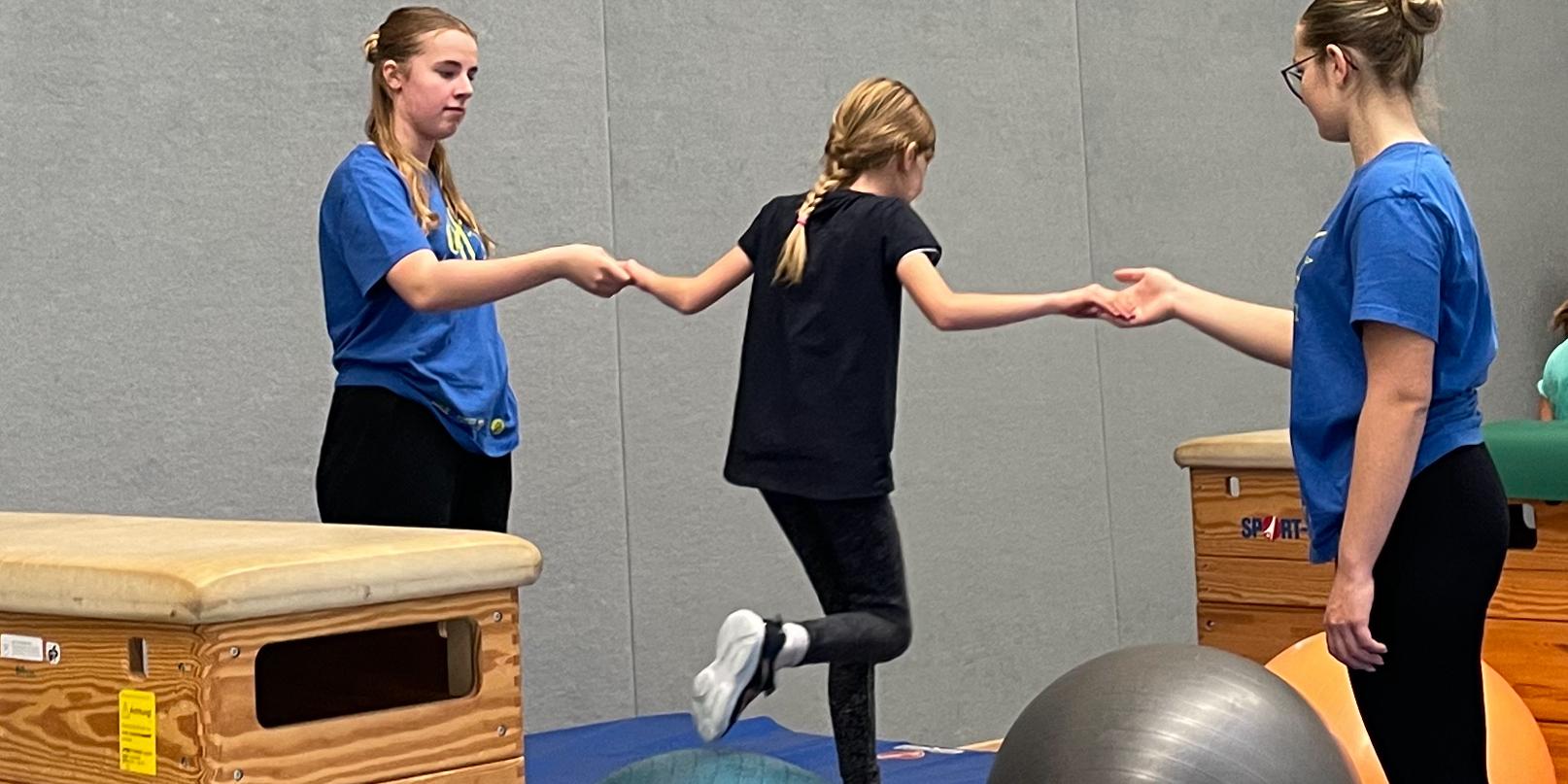 Sporthelfer:innen begleiten die Mädchen und Jungen beim Parcours.