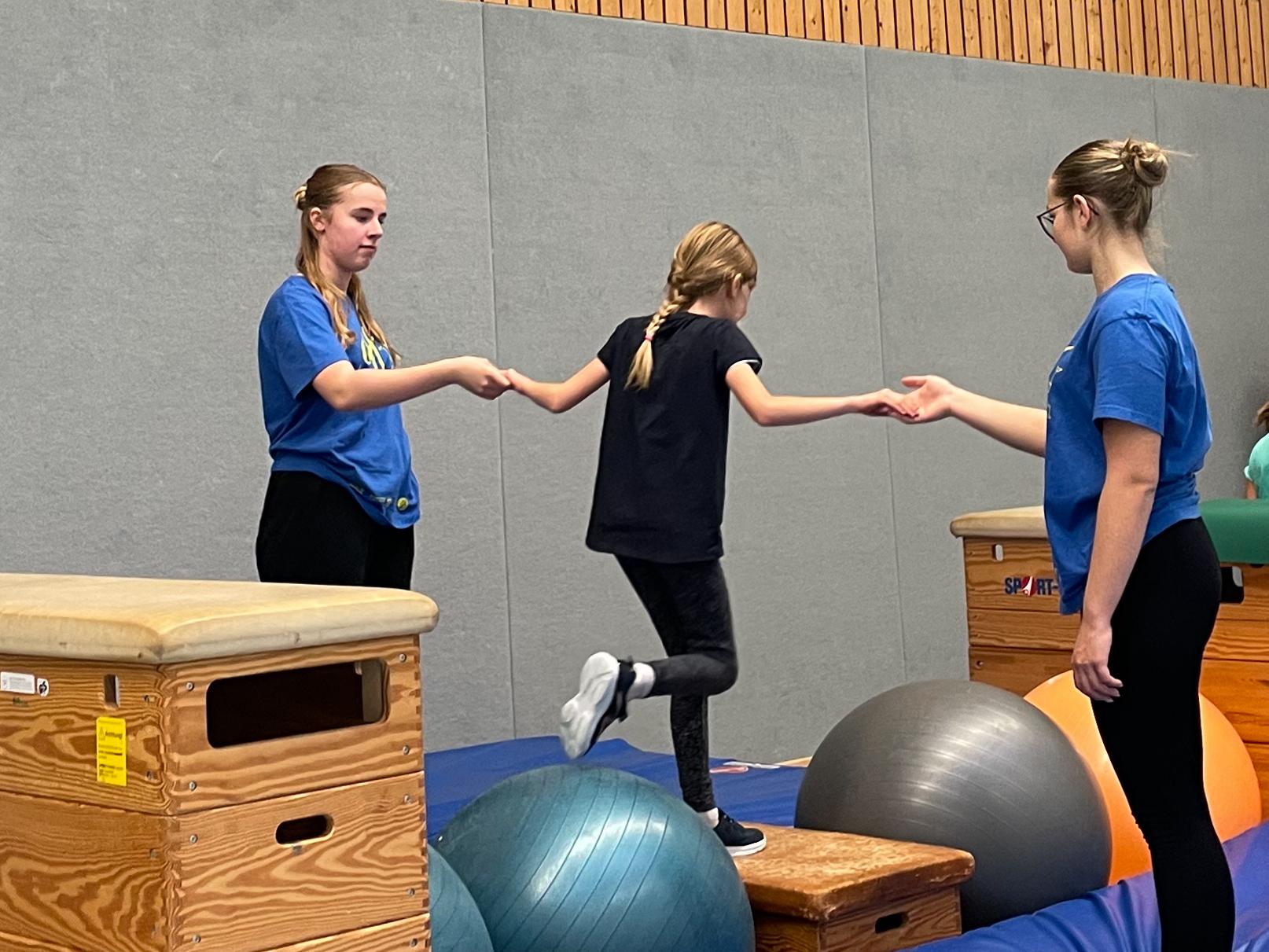 Sporthelfer:innen begleiten die Mädchen und Jungen beim Parcours.