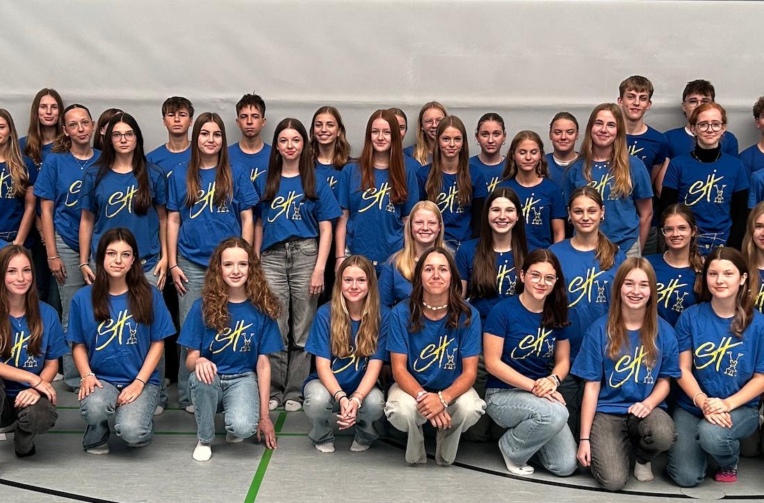 Mädchen und Jungen mit T-Shirt mit Aufdruck 'Sporthelfer' in der Turnhalle