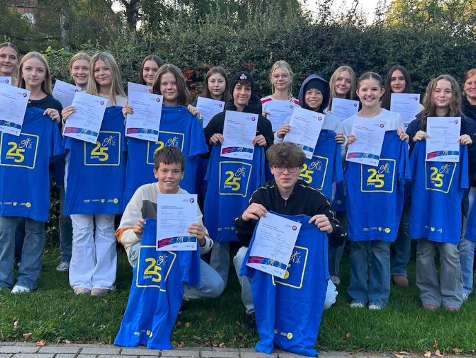 Mädchen und Jungen mit Urkunden und blauem Sporthelfer-Shirt in den Händen
