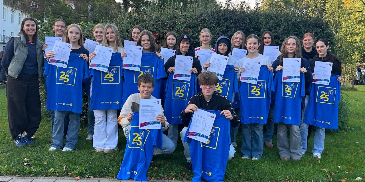 Die neuen Sporthelferinnen und Sporthelfer im Oktober 2026 Mädchen und Jungen mit Urkunden und blauem Sporthelfer-Shirt in den Händen