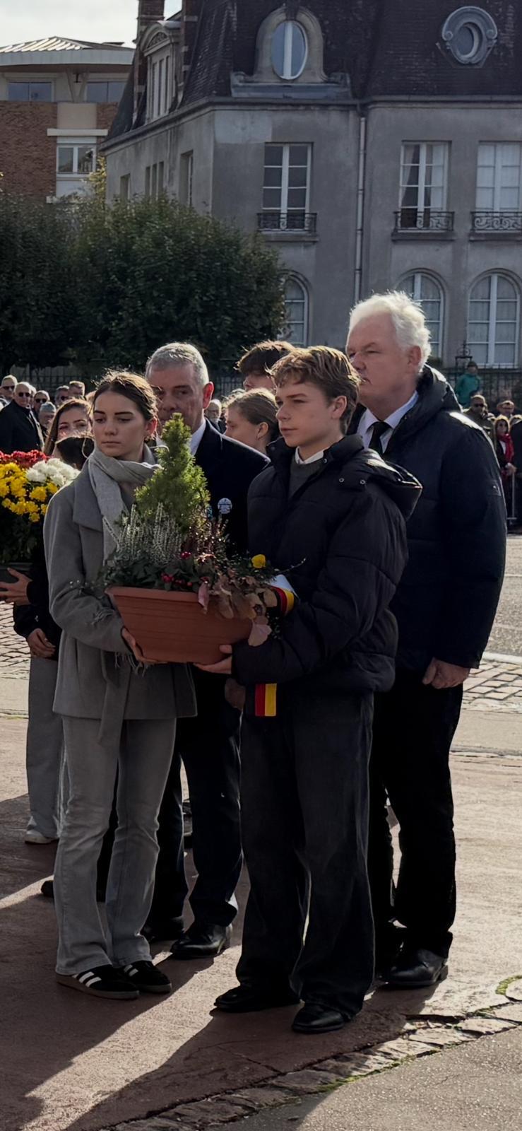 Schülerin und Schüler mit Blumenschale in der Hand dahinter vier Erwachsene