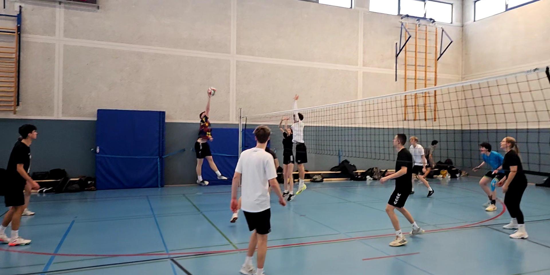 Mädchen und Jungen spielen Volleyball in einer Schulturnhalle