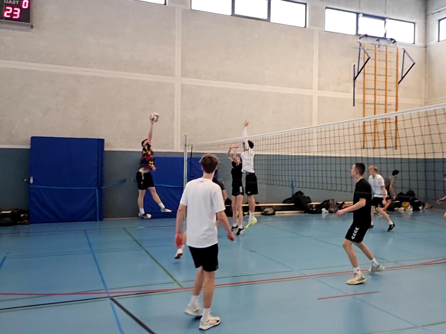Mädchen und Jungen spielen Volleyball in einer Schulturnhalle