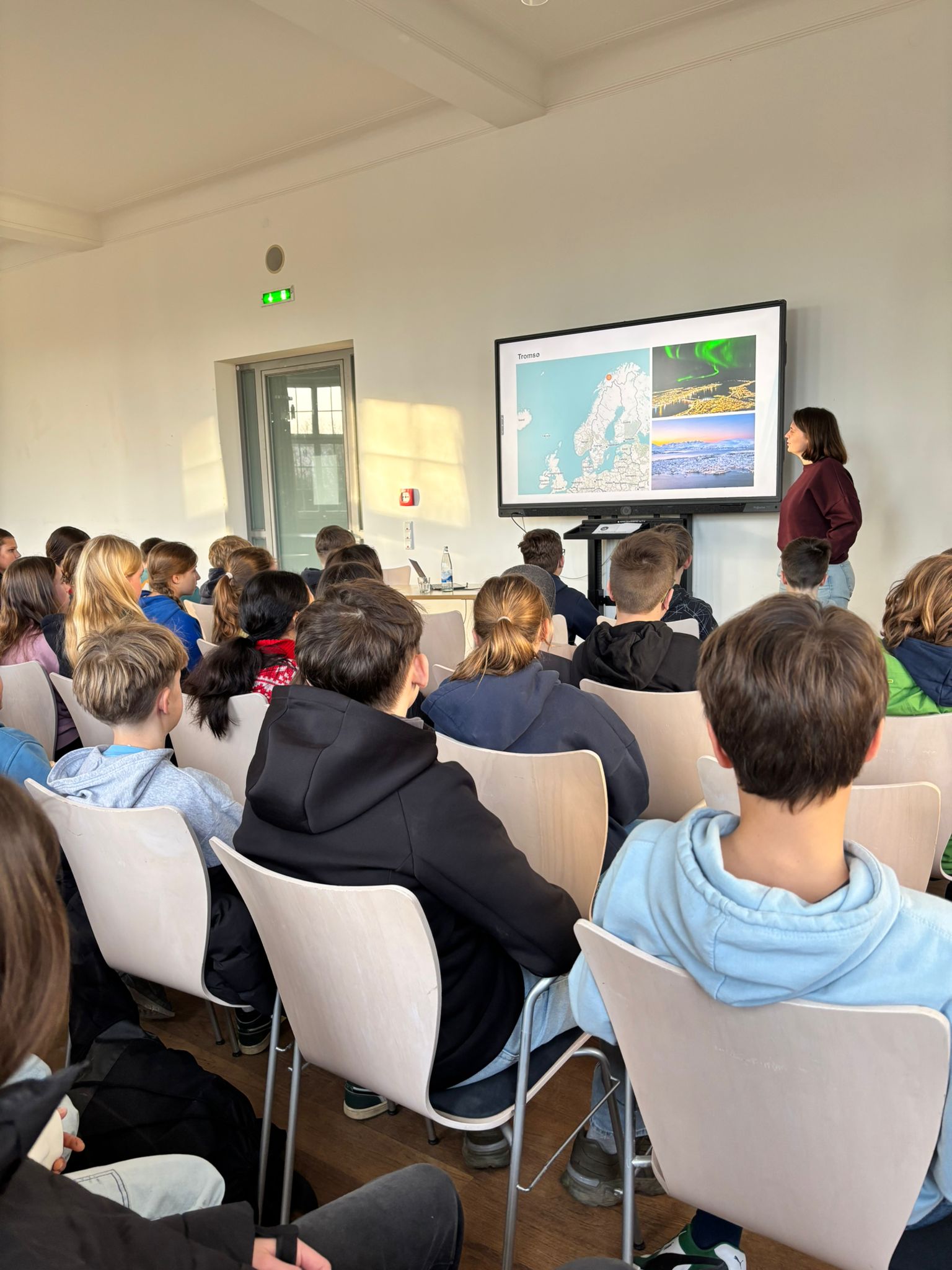Schüler in Stuhlreihen, hinten Referentin