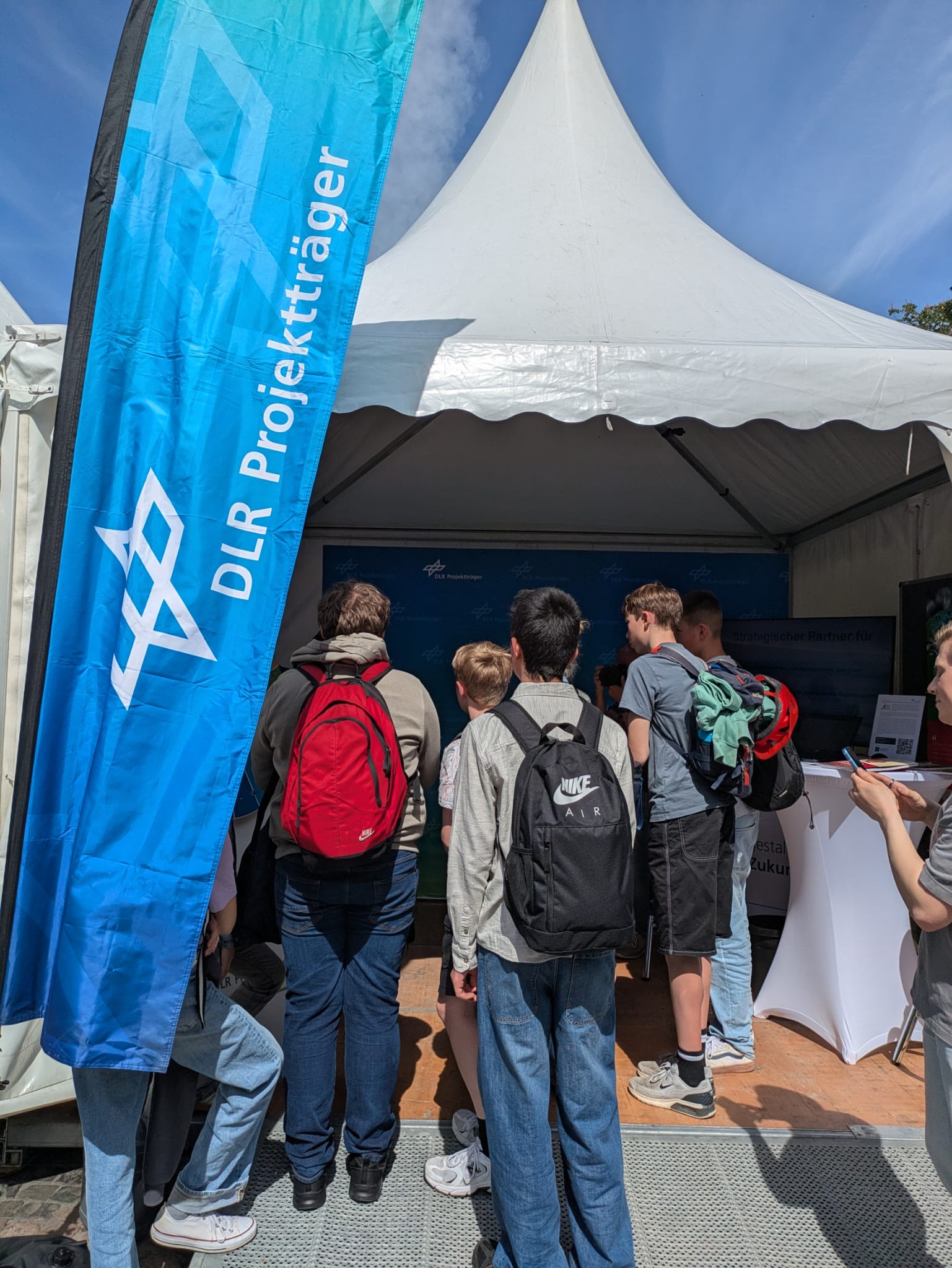 Schülerinnen und Schüler am Stand von DLR in einem Zelt