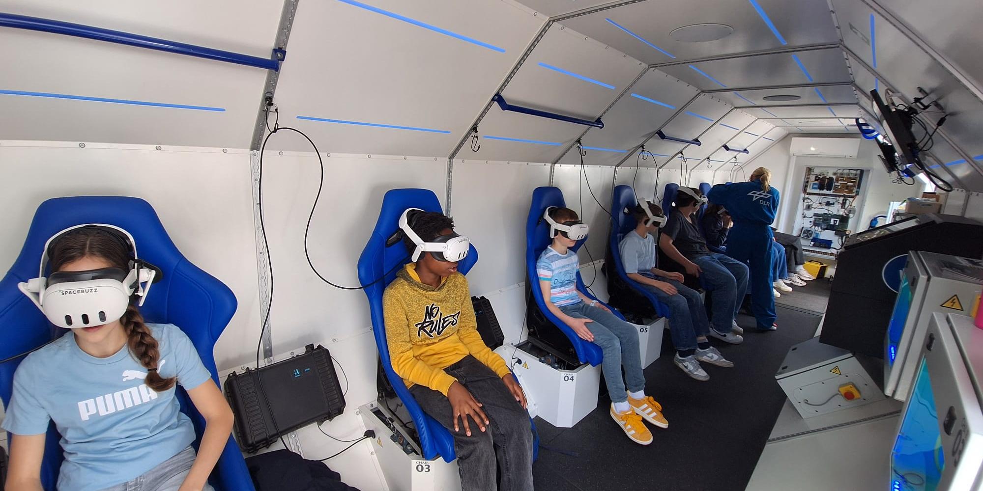 Kinder sitzen in einer nachgebauten Spacebuzz One mit VR-Brillen