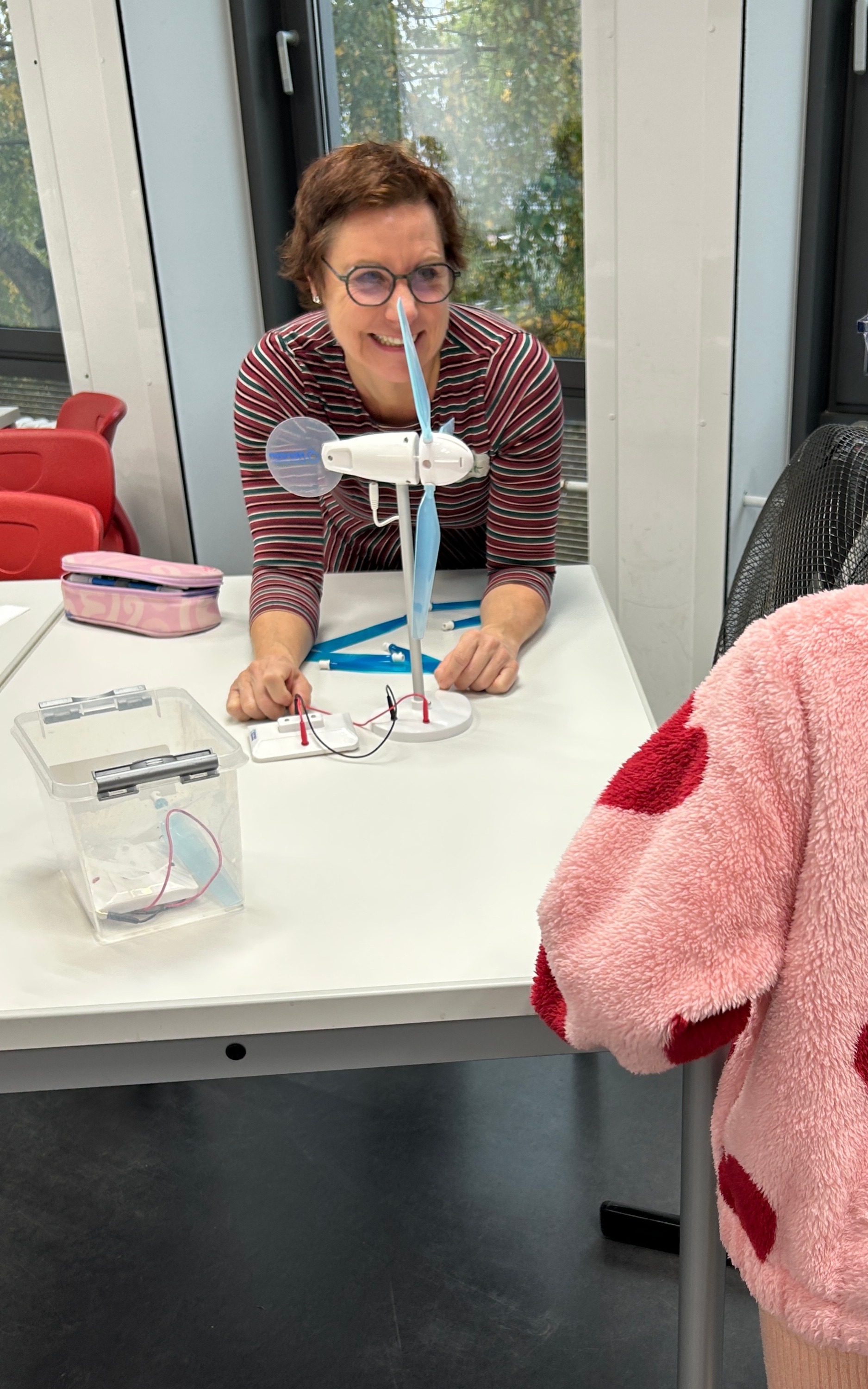 Lehrerin hinter kleinem Windrad, das auf einem Tisch steht