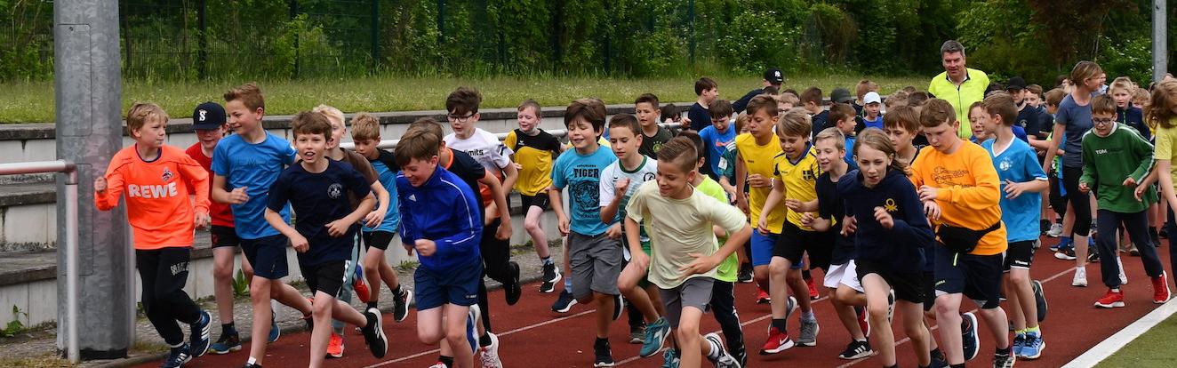 Schüler:innen laufen auf dem Sportplatz: Start des Sponsorenlaufs