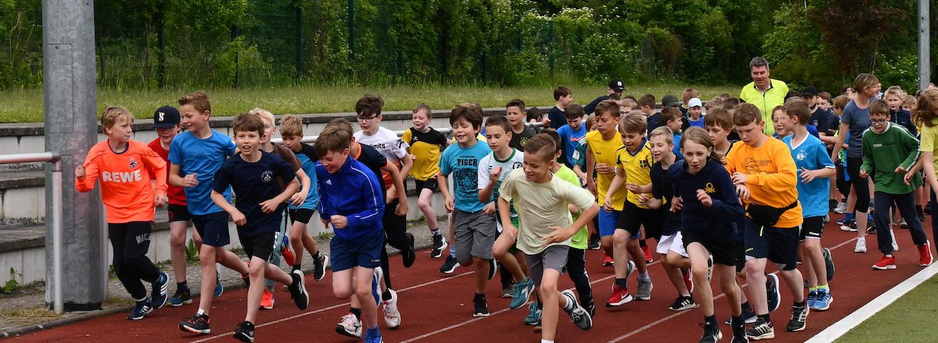 Schüler:innen laufen auf dem Sportplatz: Start des Sponsorenlaufs