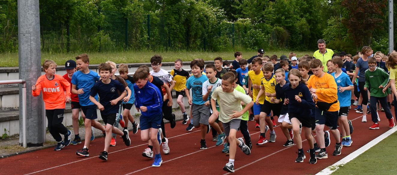 Schüler:innen laufen auf dem Sportplatz: Start des Sponsorenlaufs