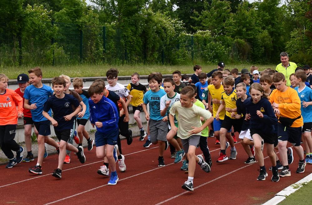 Schüler:innen laufen auf dem Sportplatz: Start des Sponsorenlaufs