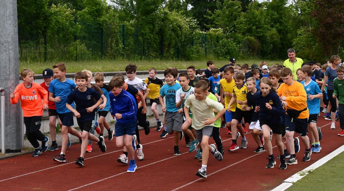 Schüler:innen laufen auf dem Sportplatz: Start des Sponsorenlaufs