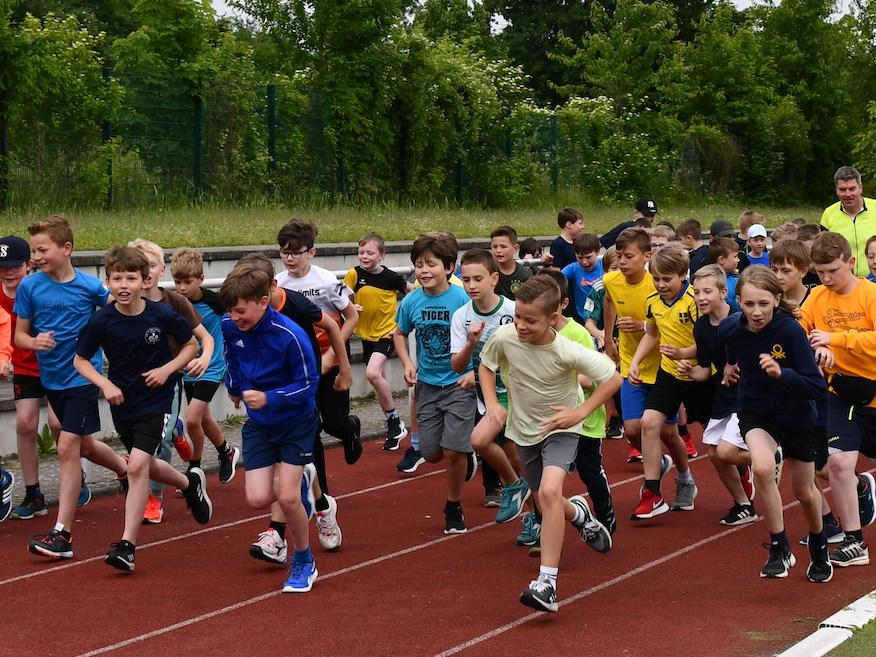 Schüler:innen laufen auf dem Sportplatz: Start des Sponsorenlaufs