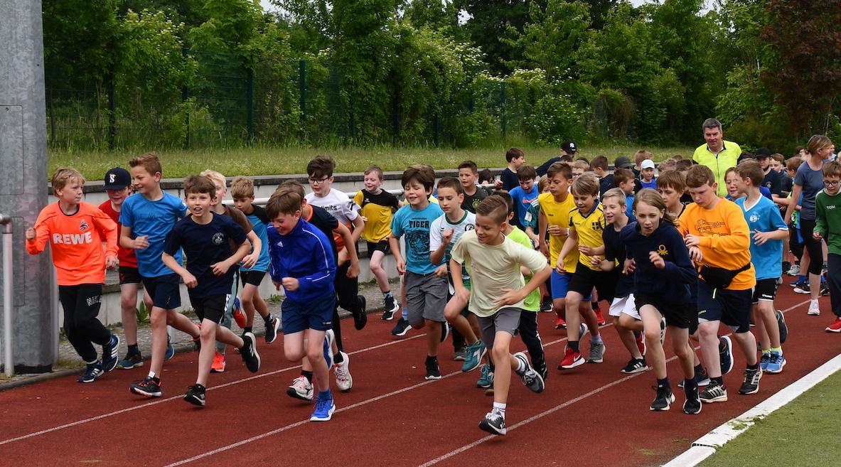Schüler:innen laufen auf dem Sportplatz: Start des Sponsorenlaufs